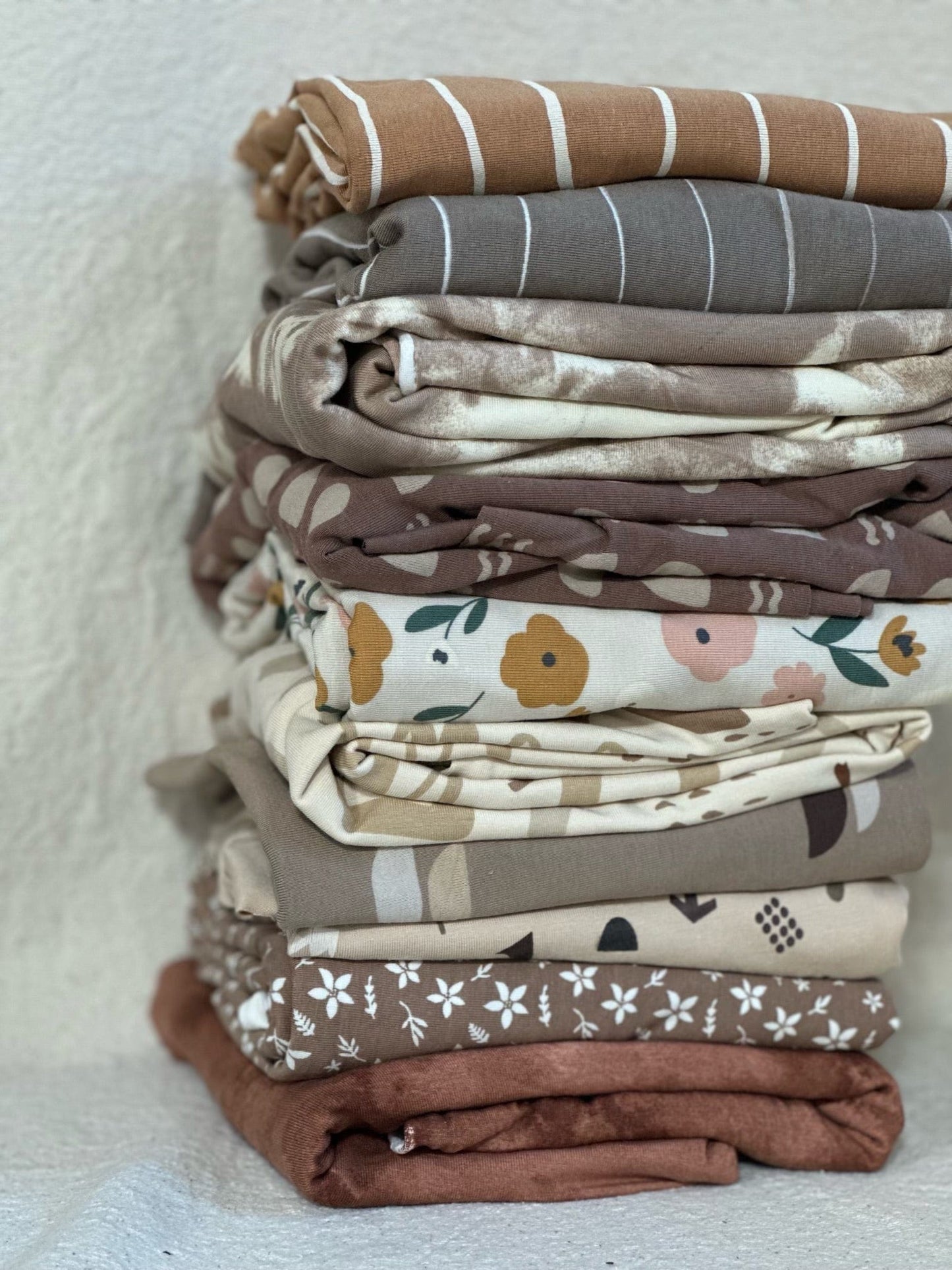 Pile of assorted patterned fabrics in earth tones