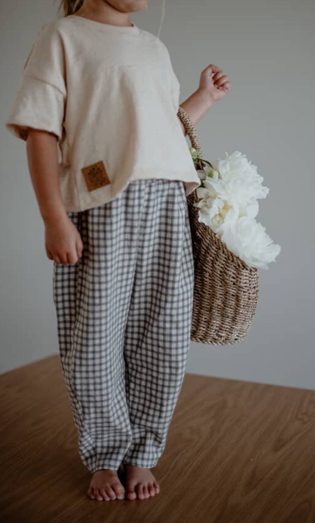 Child in gingham pants and carrying flowers