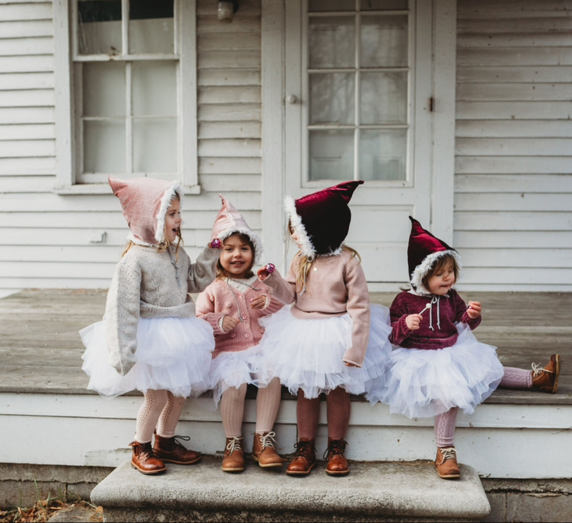 Children in tutus and hats on porch