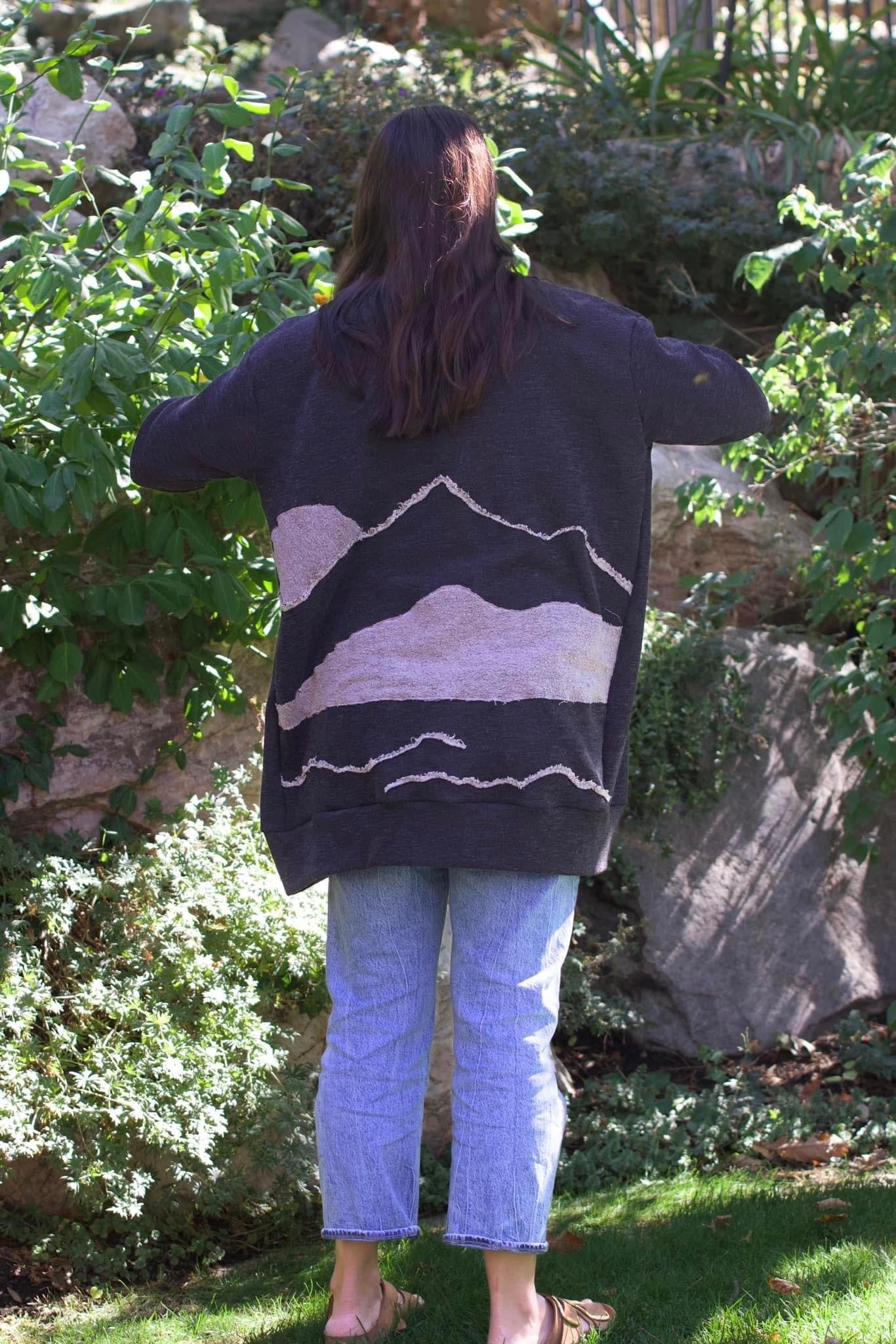 Woman wearing a dark coat with a mountain design.