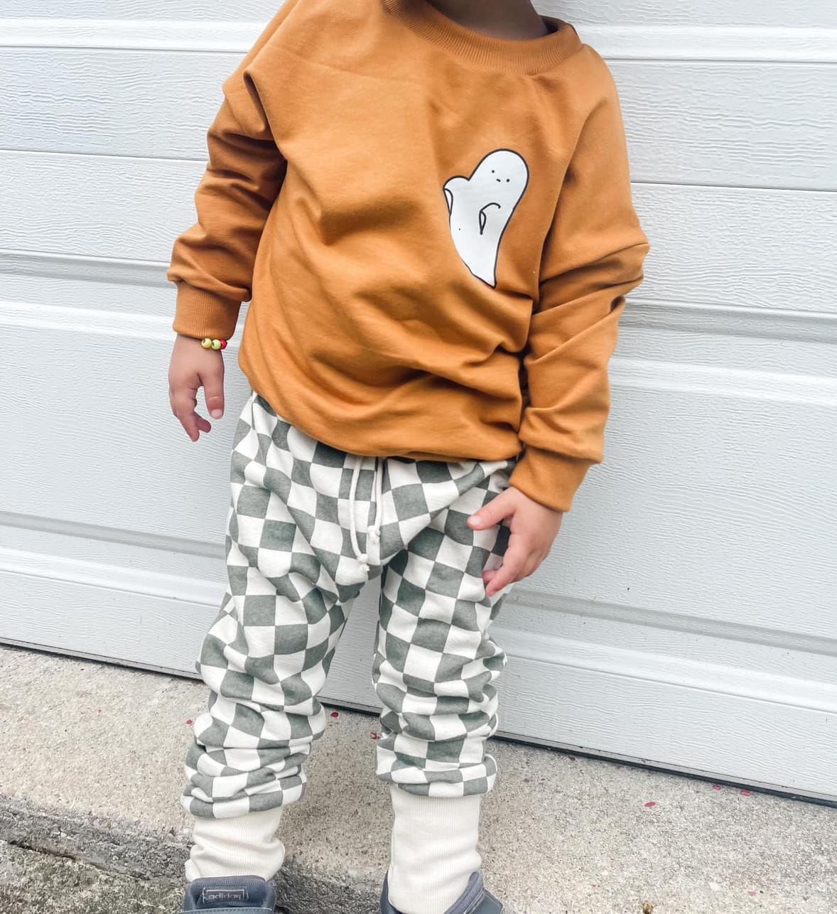Child in ghost sweatshirt and checkered pants