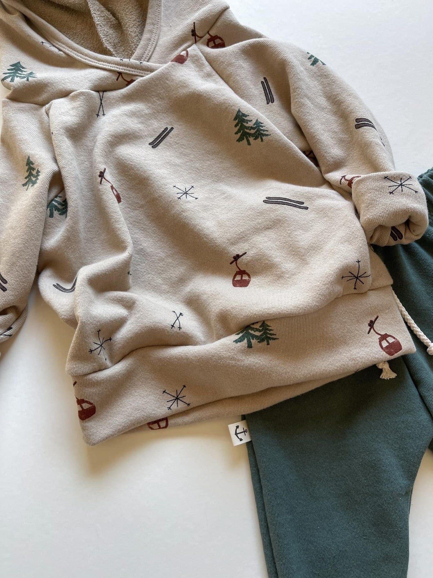 Beige hoodie and green sweatpants with ski pattern.