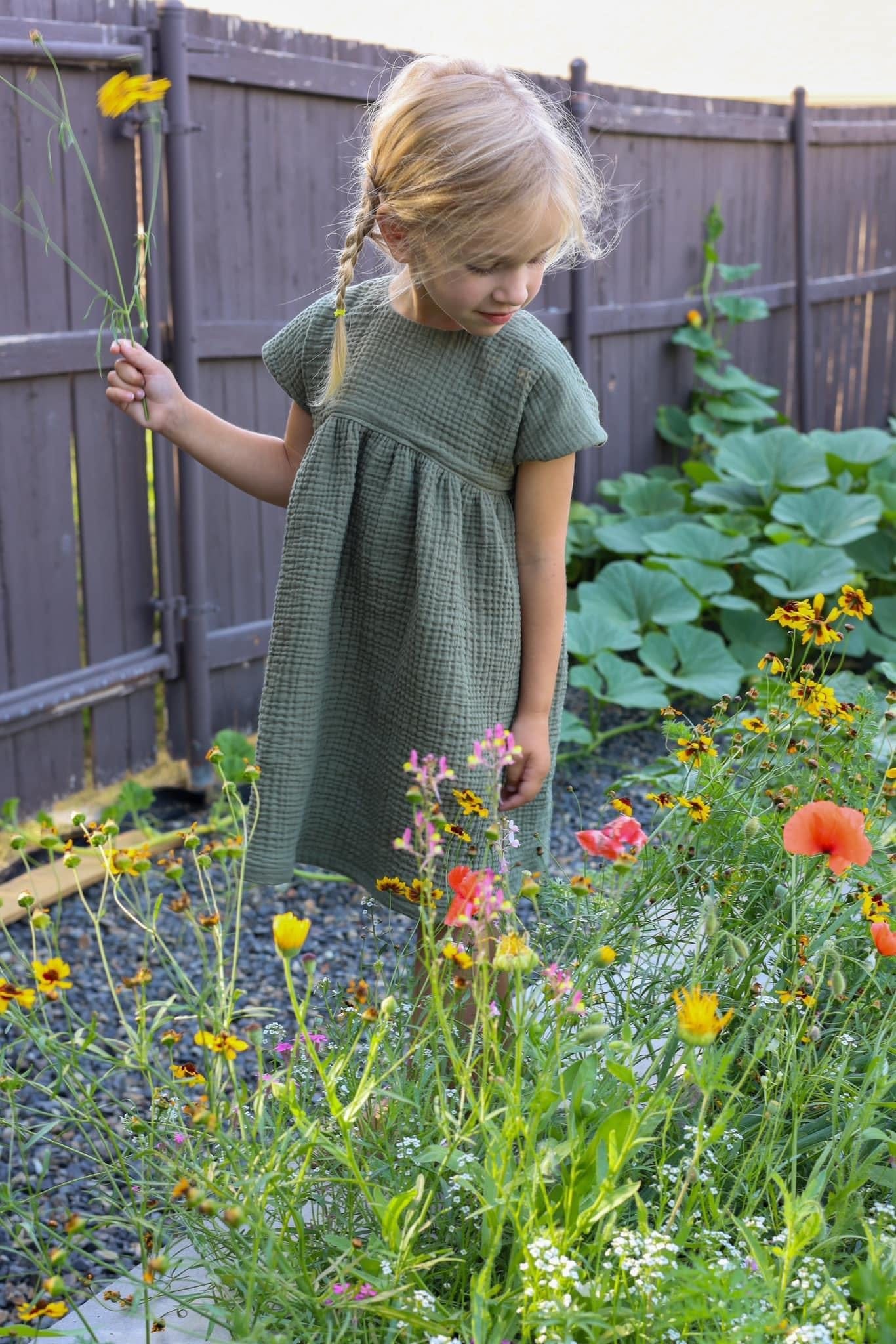 Girl in green dress in flower garden.