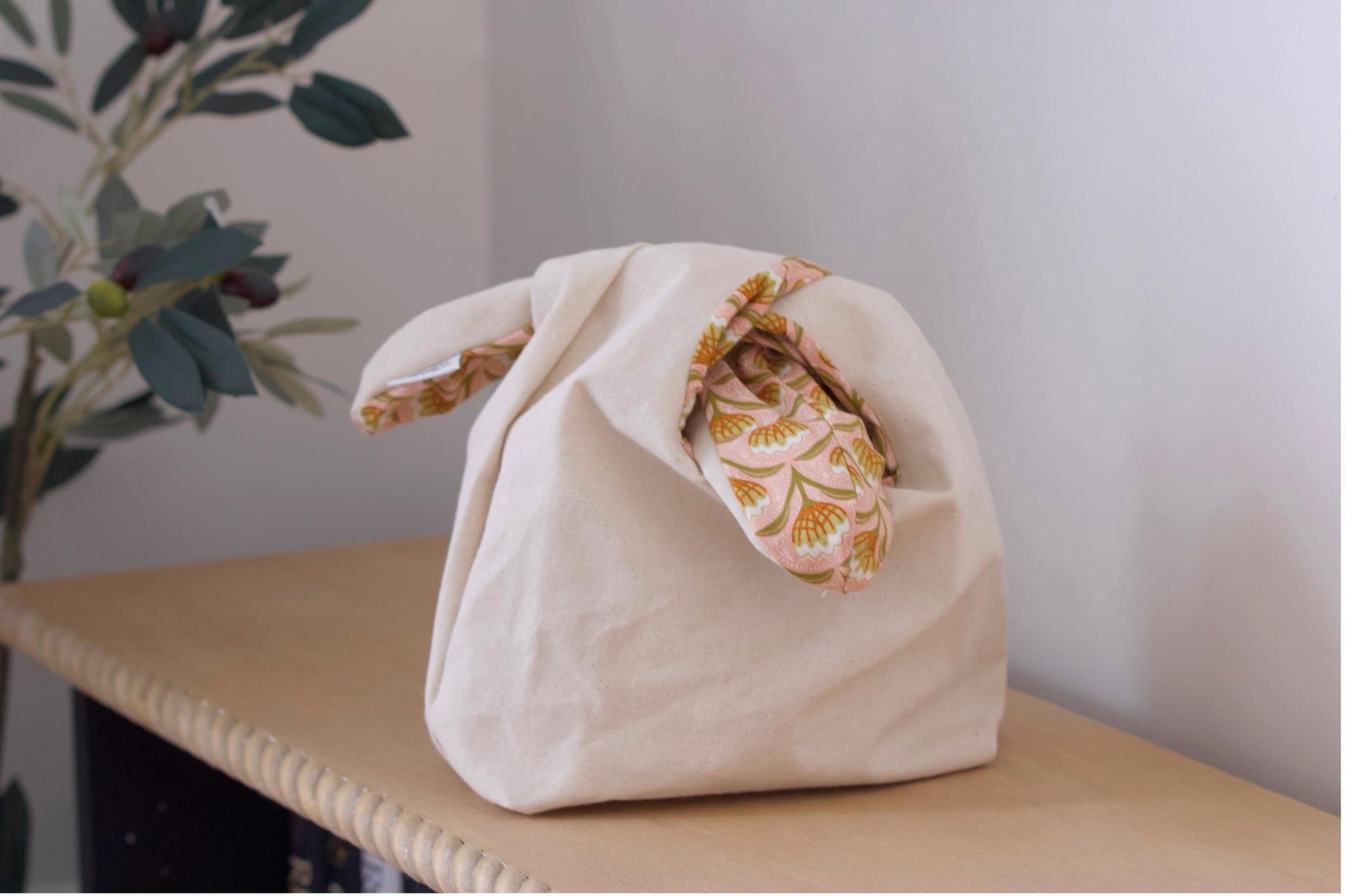 Canvas bag with floral lining on wooden shelf.