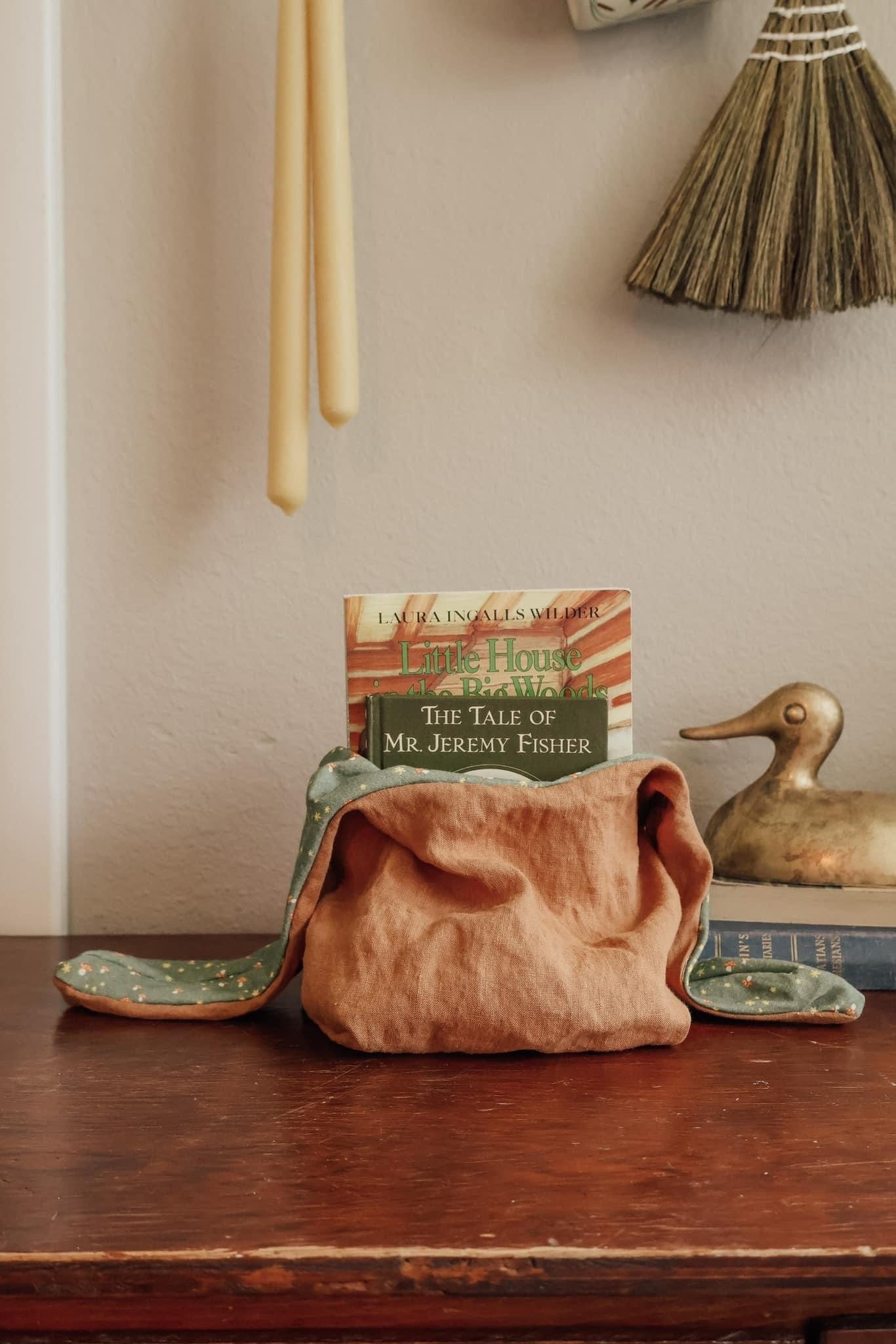 Tabletop still life with book, pouch, duck, and candles.