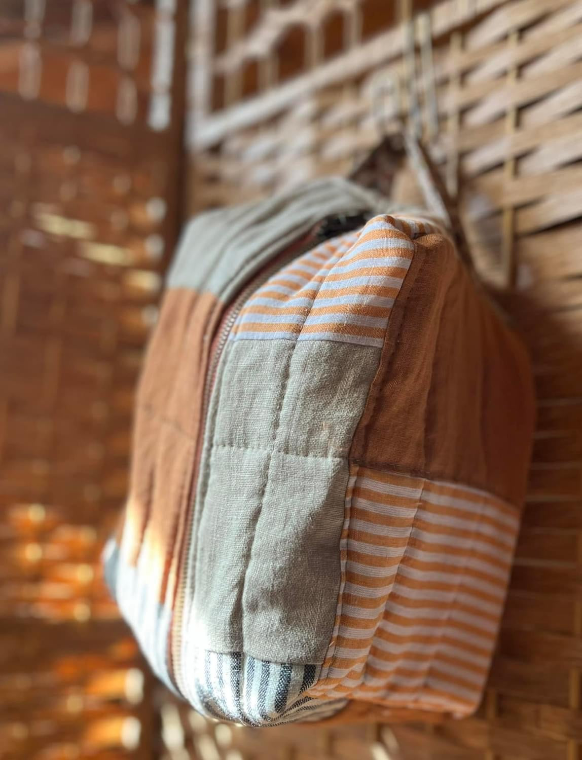 Patchwork tote bag hanging on a woven wall.