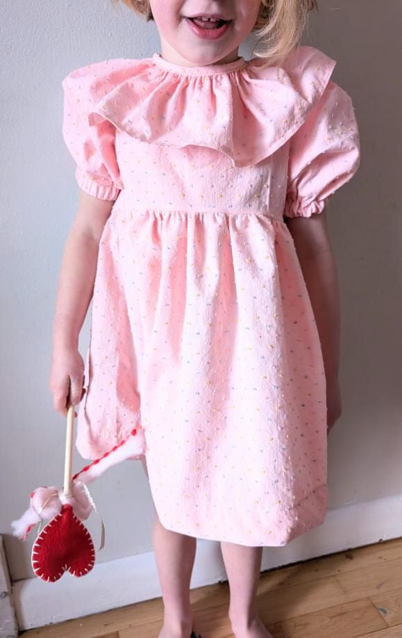 Girl in pink dress holding a heart wand.