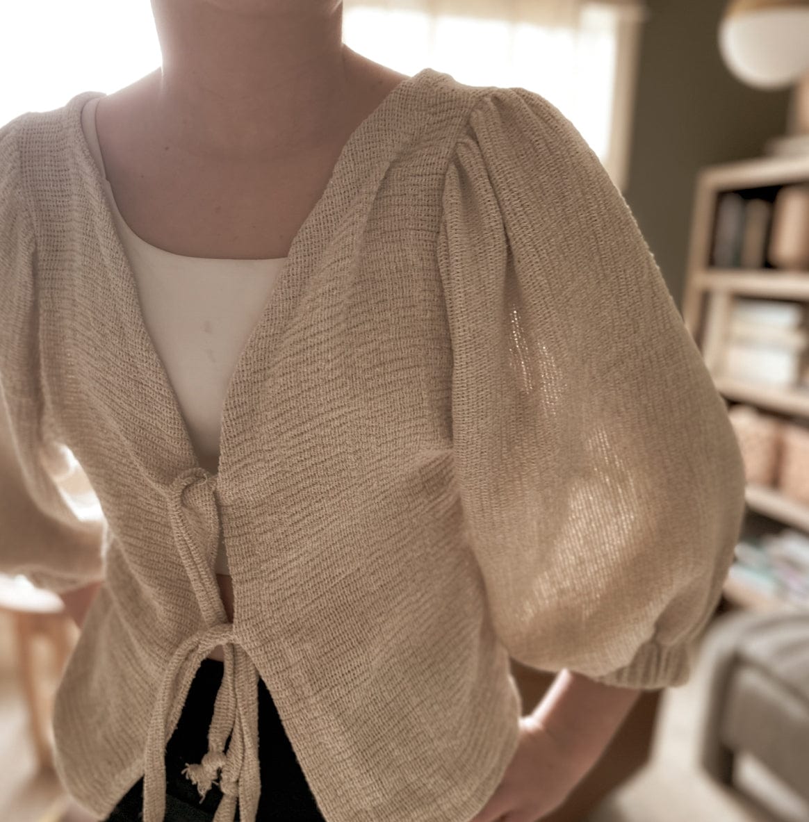 Woman wearing a beige tie-front cardigan.