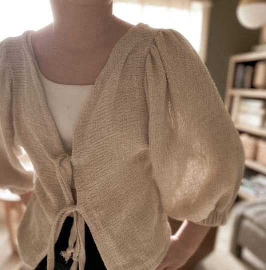 Woman wearing a beige tie-front cardigan.