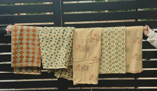 Printed fabric rolls hanging on a fence.