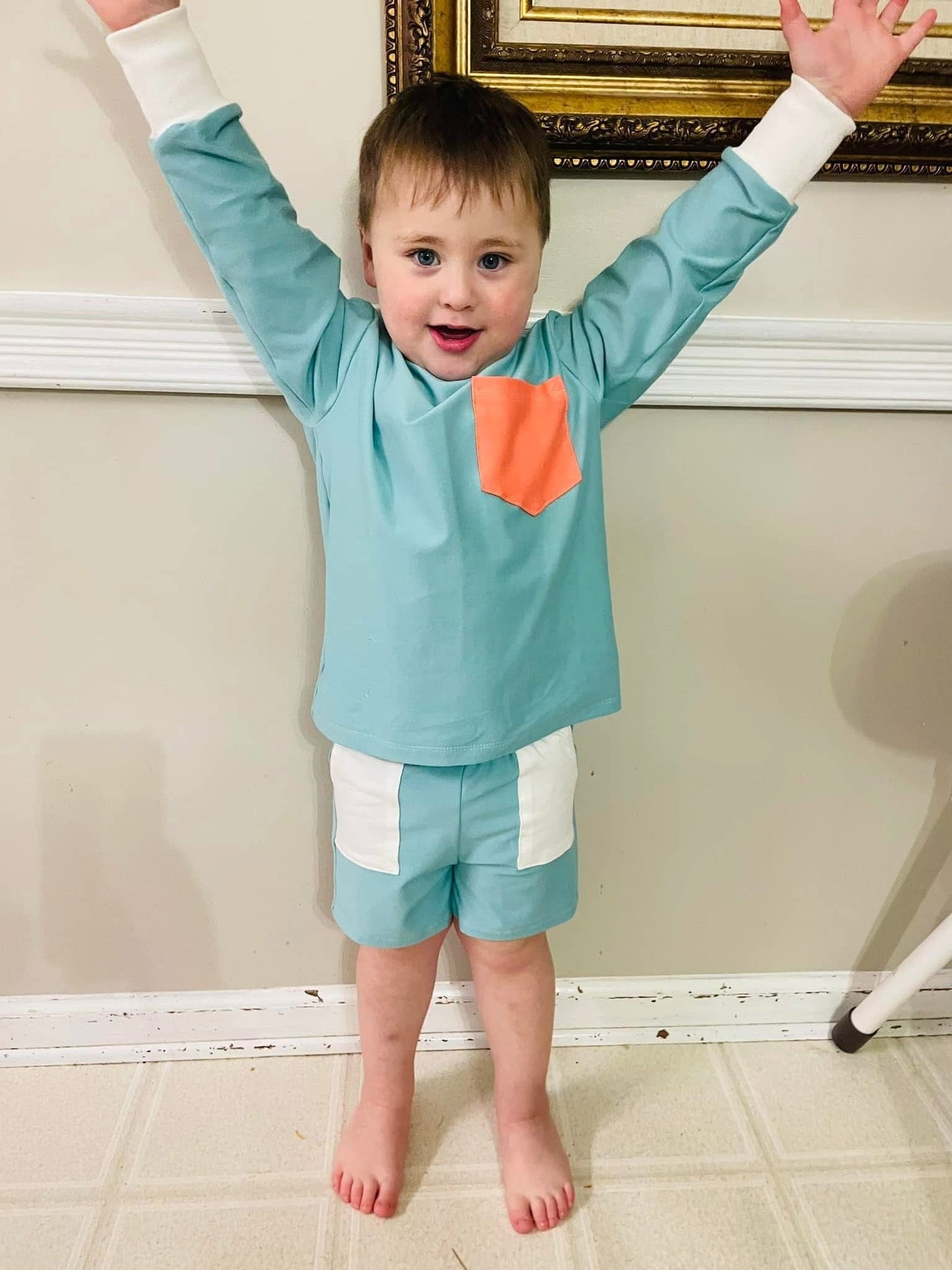 Boy in blue shirt and shorts with arms raised.