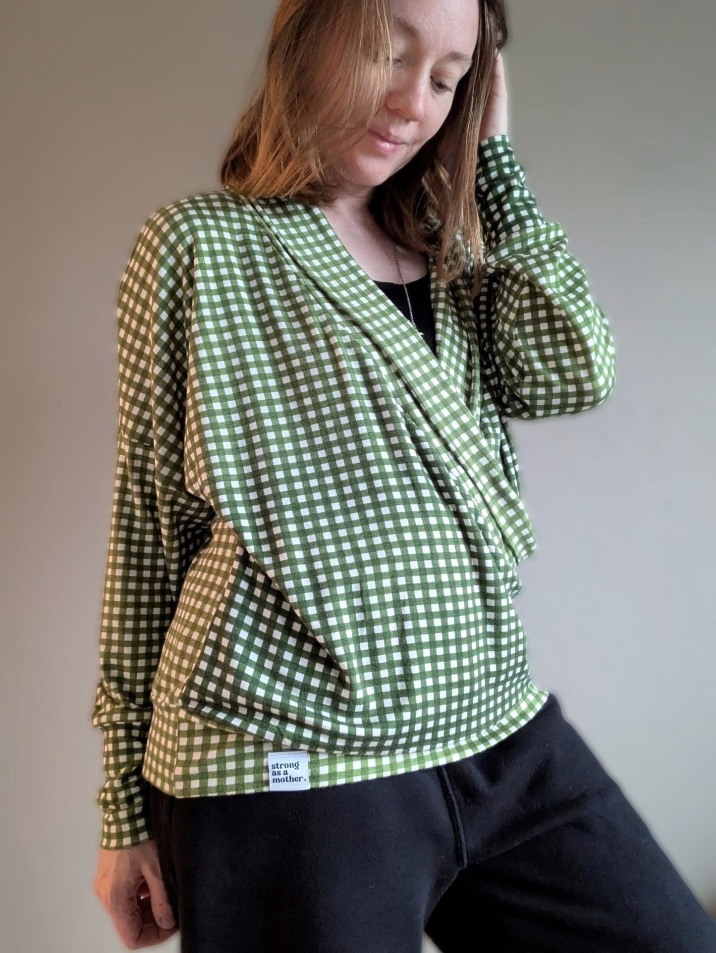 Woman wearing green gingham wrap top and black pants.