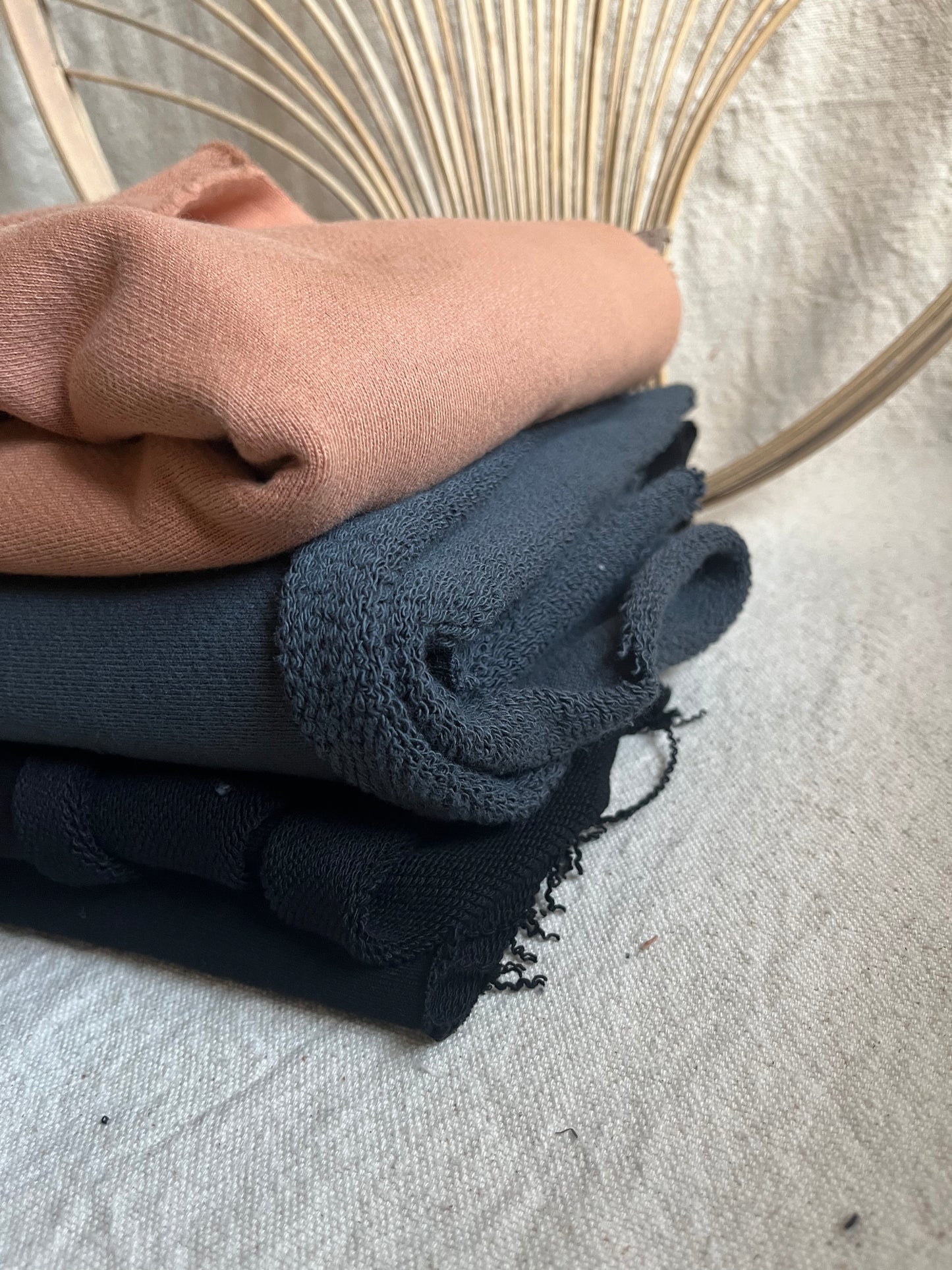 Pile of folded sweaters in shades of pink, blue, and black.