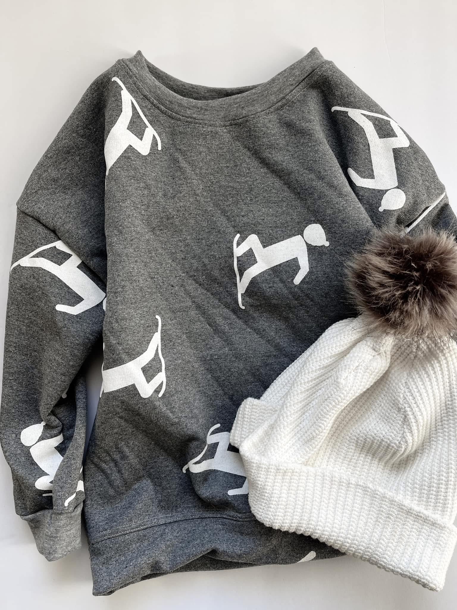 Gray sweatshirt with white figures and white beanie.