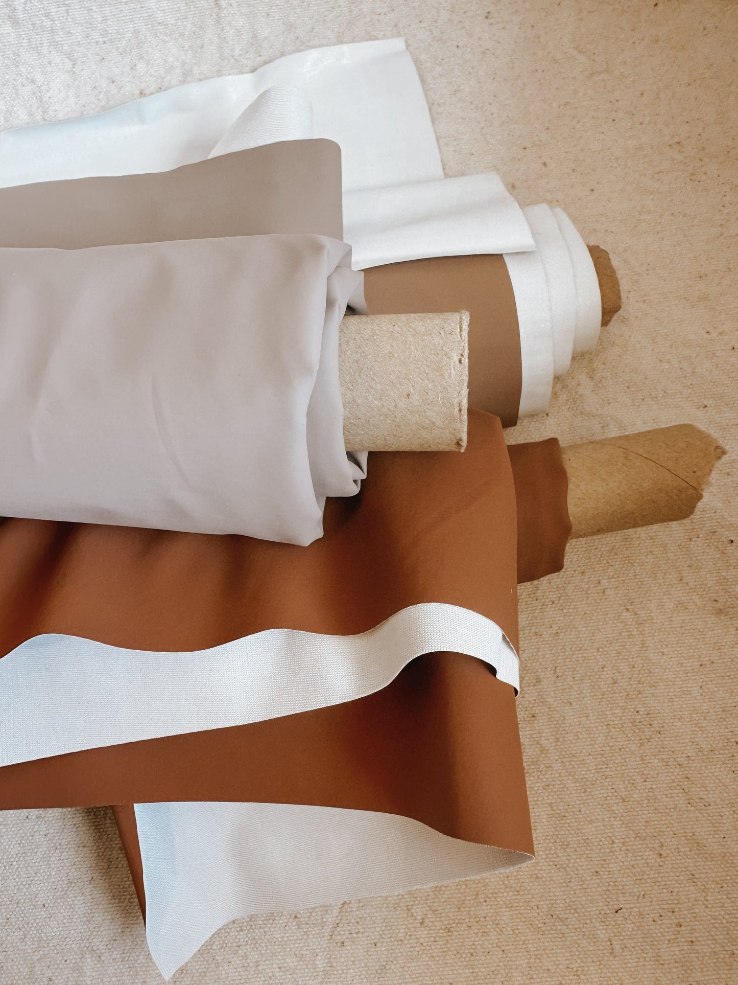 Rolled fabric in shades of white, beige, and brown.