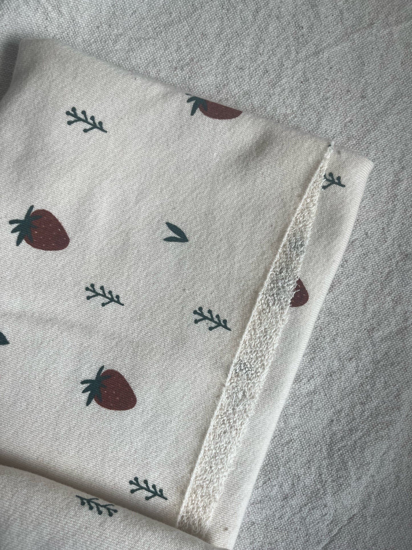 White fabric with strawberries and leaves pattern.