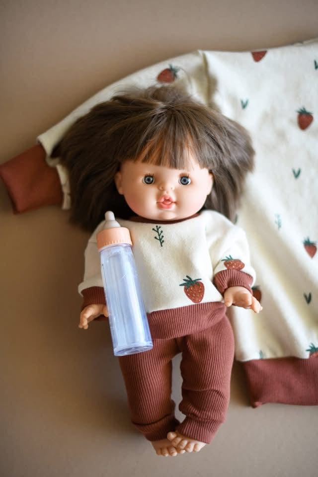 Doll in strawberry outfit holding a bottle.