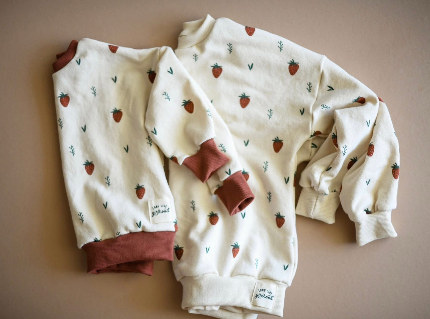 Two cream-colored sweatshirts with strawberry pattern.