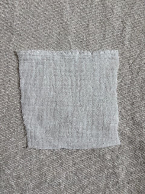 Square of white fabric on gray fabric.