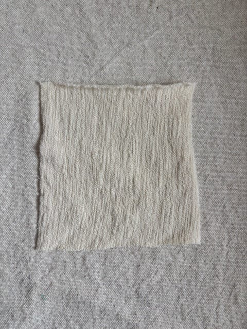White, textured fabric square on gray background.
