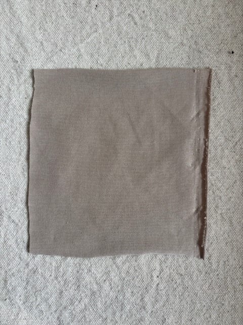 Square piece of brown fabric on a textured background.