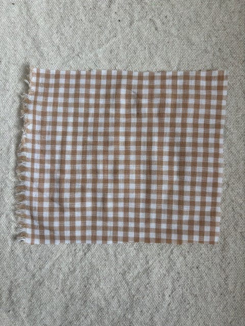 Brown and white gingham fabric on a textured surface.