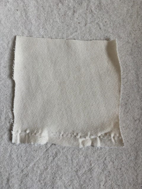 Square piece of white fabric with frayed edges.
