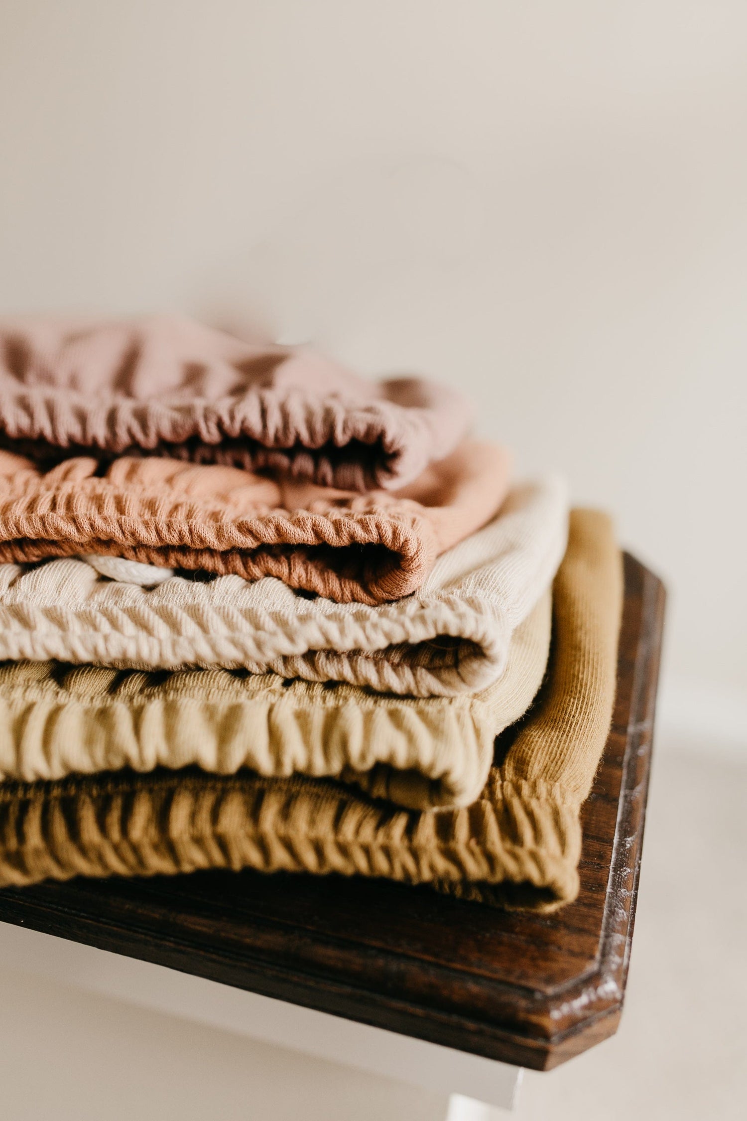 Mae - 100 FT line up of folded linen fabrics in various neutral colors.