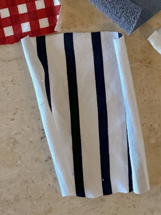 Close-up of folded white fabric with navy stripes, part of fabric collection.