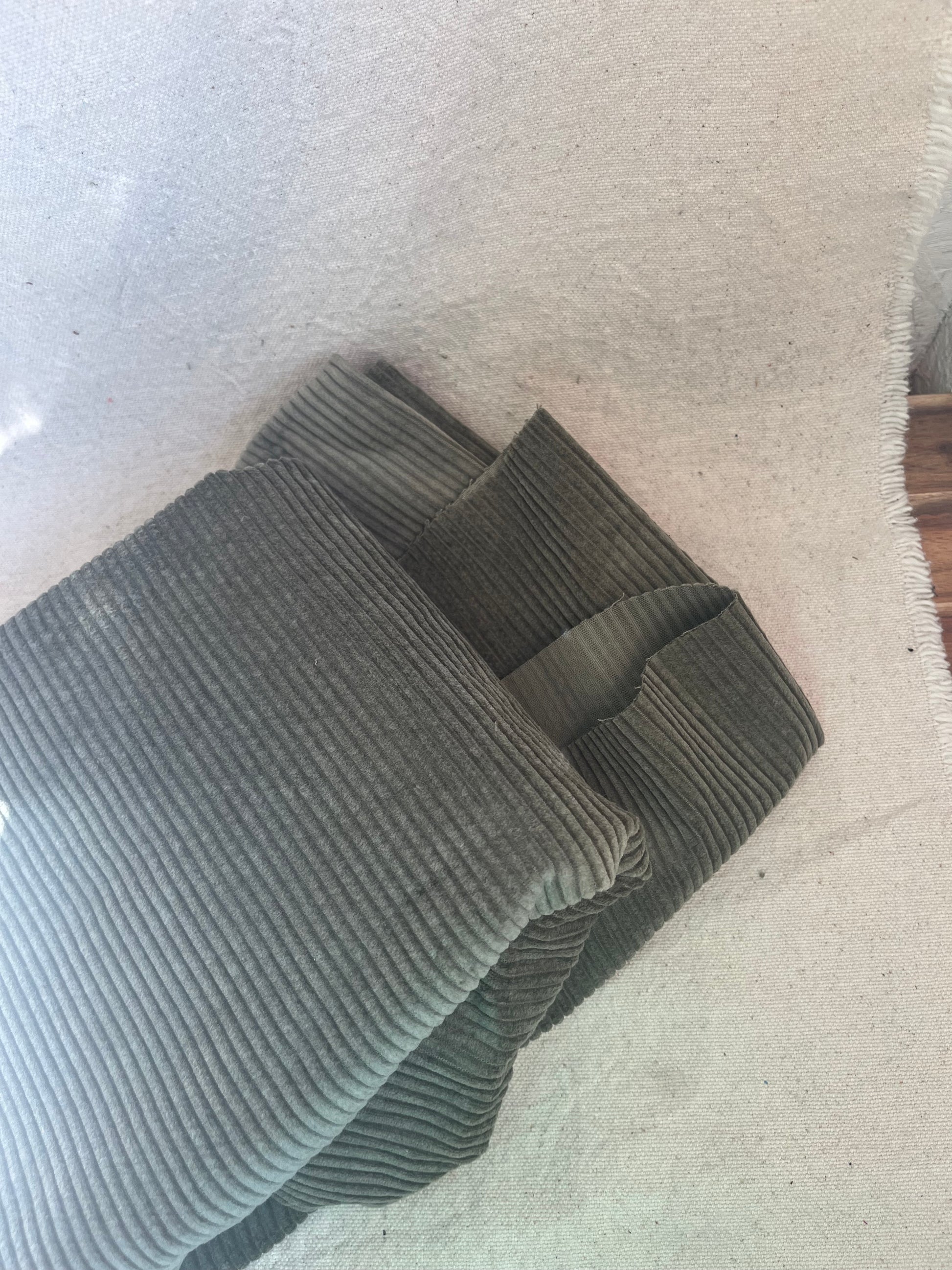 Folded gray corduroy fabric on white cloth.